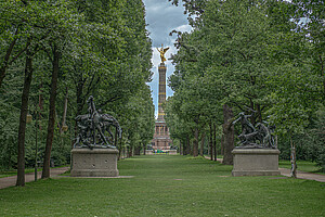 Tiergarten mit Blick auf die Siegessäule Ein breiter, von Bäumen gesäumter Weg im Berliner Tiergarten führt zur goldenen Siegessäule, flankiert von zwei großen Reiterskulpturen.