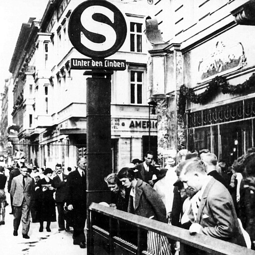 Neugier am neuen Bahnhof Unter den Linden Für den Boulevard Unter den Linden gestaltete der Reichsbahn-Architekt Richard Brademann die Treppenzugänge des gleichnamigen Bahnhofs (heute Brandenburger Tor) in schlichter Schönheit. Um die Brüstung eines Zugangs drängt sich neugieriges Publikum.