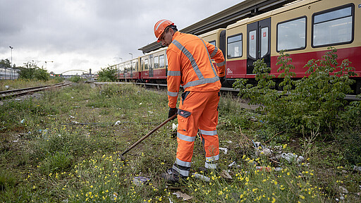 Mit der Harke gegen den Müll DB Gleisreiniger Marcus Zehle vor einfahrender S-Bahn am S-Bahnhof Warschauer Straße.