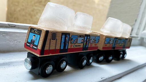Sina-Spielzeug-S-Bahn mit Eiswürfeln darauf gelegt