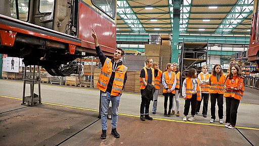 Girls’Day Akademie 2023 Azubi Paul Heidekrüger (l.) erklärt unter anderem, wo an einem Zug der BR 480 die Rampe für Rollstuhlfahrer:innen ausfährt.