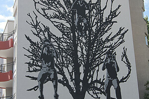 Ein Bild von einem Baum mit drei Kindern in einem schwarz-weißen Schablonenstil an einer Wand