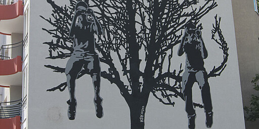 Ein Bild von einem Baum mit drei Kindern in einem schwarz-weißen Schablonenstil an einer Wand