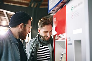 Ticketautomat Zwei Personen schauen auf den Bildschirm eines Ticketautomaten