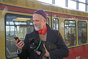 Ein Mann trägt einen kleinen schwarzen Hund