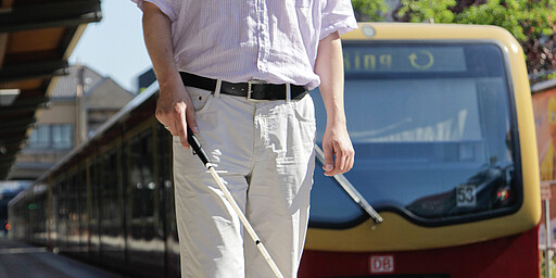 Sehbehinderter Sehbehinderter mit Blindenstock auf dem Bahnsteig, Blindenleitsystem