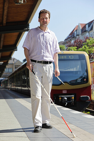 Sehbehinderter Sehbehinderter mit Blindenstock auf dem Bahnsteig, Blindenleitsystem