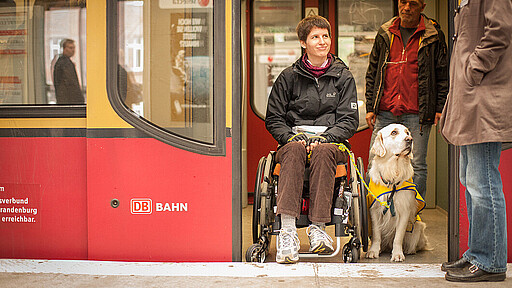 Woman in a wheelchair accompanied by a dog A woman in a wheelchair is accompanied by a dog in the train.
