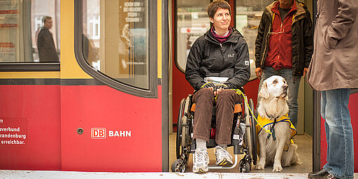 Woman in a wheelchair accompanied by a dog A woman in a wheelchair is accompanied by a dog in the train.