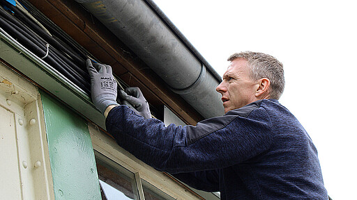 Silvio Jesse bringt eine Metallblende an einem Kabelschacht an.