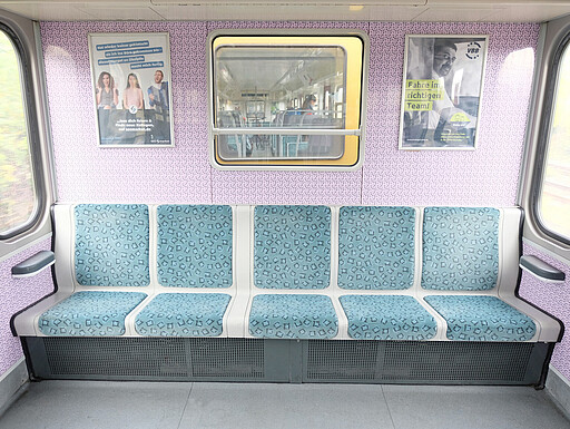 485 Sitzbank Die breite durchgehende Sitzbank am Ende eines 485er-Wagens, umrahmt vom Berlin-Wimmeldesign.