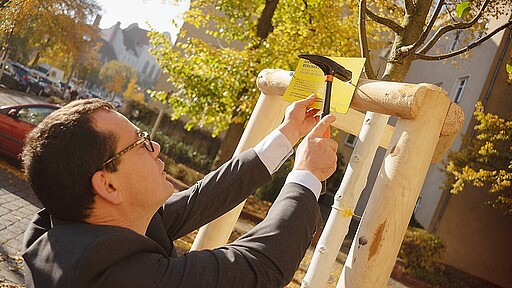 Umweltinitiative S-Bahn-Chef Peter Buchner bringt ein Schild an, das für die Stadtbaumkampagne wirbt.
