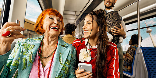 Ein Jahrhundert Eine jüngere und eine ältere Person sitzend lacehnd in der neuen S-Bahn.