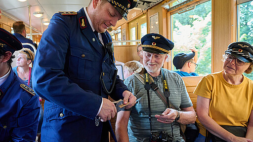 Kontrolle mit Stil. Aurel Gröne in alter Uniform knipst Fahrkarten auf der Fahrt im historischen Zug.