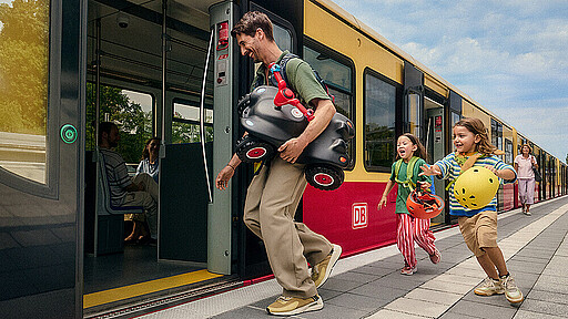 Ein Vater, der mit einem Bobbycar und zwei Kindern in die S-Bahn einsteigt Ein Vater, der mit einem Bobbycar und zwei Kindern in die S-Bahn einsteigt