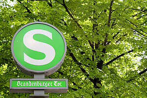 Schild zum S-Bahnhof Brandenburger Tor mit Bäumen im Hintergrund