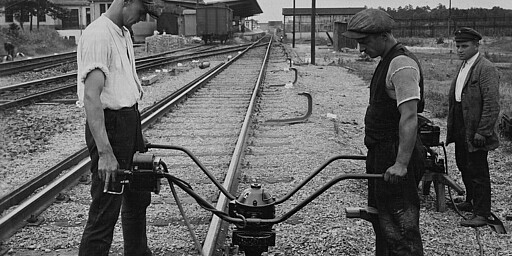 Two men install a conductor rail, ca. 1928