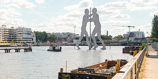  Die in der Spree stehende Skulptur Molecule Man personifiziert das Aufeinandertreffen der drei damaligen Bezirke Treptow, Kreuzberg und Friedrichshain. 