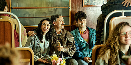 Der Mauerfall Zwei Personen sitzen glücklich und sich im Arm haltend in der S-Bahn.