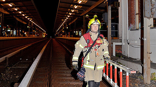 Mit einer Leiter steigen die Kräfte der Feuerwehr in das Gleisbett hinab.