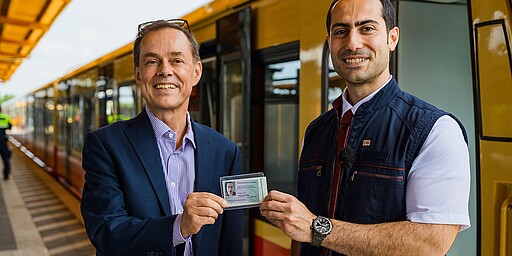 S-Bahnchef Peter Buchner überreicht dem eintausendsten Lokführer Mohammad Omidi nach bestandener Prüfung den Führerschein.