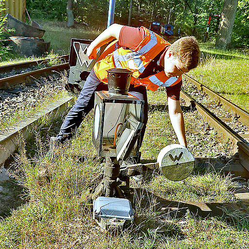 Da die Parkeisenbahn noch ein mechanisches Stellwerk hat, muss Dennis Redler die Weiche von Hand stellen.