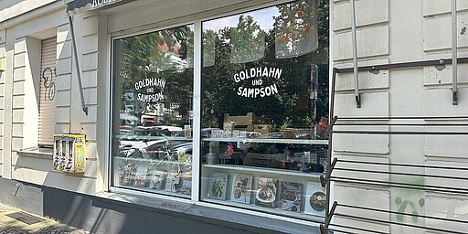 Goldhahn & Sampson Prenzlauer Berg  In den Schaufenstern des Goldhahn & Sampson sind verschiedene Produkte wie Kochbücher und Küchenutensilien zu sehen.