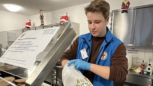 Bahnhofsmission Essensausgabe Jonas packt Brottüten.