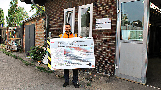 Jörg Schulze zeigt ein Schild für die Information bei Ersatzverkehr mit Bussen.