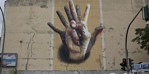 Unter der Hand  Ein Bild von zwei sich überlappenden Händen an einer Wand