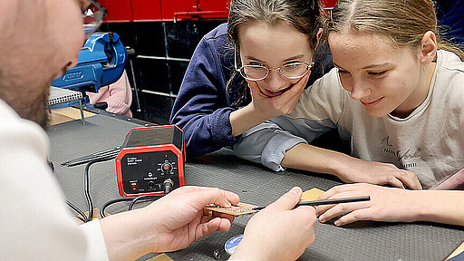 Nach der Führung kommt die Praxis Ausbildungsfachkoordinator André Wolfram erklärt Lydia und Nathalie von der Gustav-Heinemann-Oberschule, wie man die Platine bearbeitet.