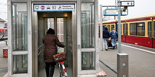 Frau mit Fahrrad geht in den Aufzug am S-Bahnhof Hennigsdorf
