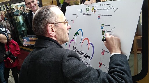 Bürgermeister Wilfried Gehrke unterschreibt auf der Jubiläumstafel.