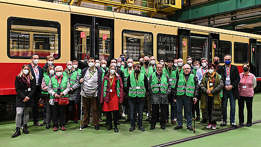 Runderneuerung vor und auf der Schiene Alte und neue Beiratsmitglieder posieren zum Gruppenfoto vor einer runderneuerten S-Bahn der Baureihe 481