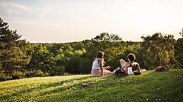 Zwei junge Menschen liegen auf einer Wiese und genießen einen lauen Sommerabend