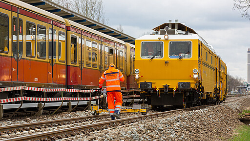 DB Bahnbau Gruppe: Stopfmaschine und Mitarbeiter beim Vermessen der Gleislage und Erstellung der Korrekturwerte für die Stopfmaschine