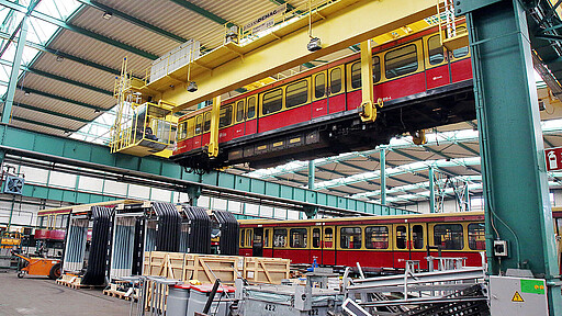 Ein Teilzug hängt an einem Krann im Instandhaltungswerk Schöneweide