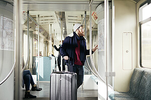 Junger Mann fährt mit einem Koffer S-Bahn