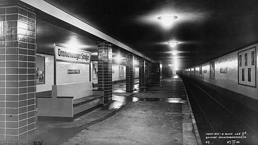 Letzter Glanz vor der Eröffnungsfahrt Am 27. Juli 1936 spiegelt sich auf dem Bahnsteig Oranienburger Straße das Licht im Restwasser vom letzten Wischgang unmittelbar vor der Eröffnungsfahrt. Orange ist die Kennfarbe der Station, welche der Reichsbahn-Architekt Richard Brademann ausgewählt hat.
