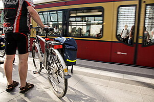 Junger Mann mit seinem Fahrrad am Bahnhof