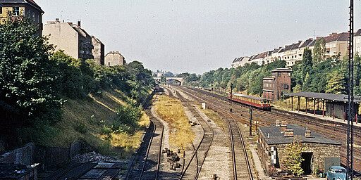 Hermannstraße Blick 1971 von der Hermannbrücke zur Oderstraßenbrücke. Links sind die Reste des Anfang 1955 geschlossenen Bahnsteigs der Neukölln-Mittenwalder Eisenbahn zu sehen. In den Bahnhof Hermannstraße fährt ein Halbzug der Ringbahn BR 275 ein.