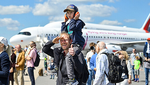 Familienausflug in die Welt der Luftfahrt Begeisterte Besucher erleben die ILA Berlin hautnah – ein Vater trägt seinen Sohn auf den Schultern und gibt ihm so den besten Blick auf die faszinierende Welt der Luft- und Raumfahrt.
