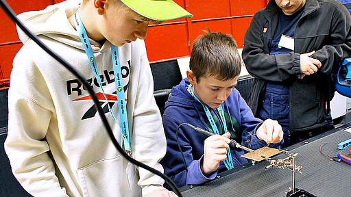 Cody (Mitte) lötet konzentriert – er interessiert sich für den Beruf des Industrieelektrikers.