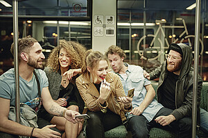 Eine Gruppe junger Leute fährt lachend mit der S-Bahn