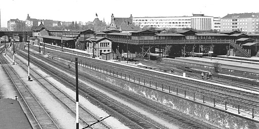 Gesundbrunnen Blick vom Güterbahnhof der Ringbahn auf den Personenbahnhof Gesundbrunnen in den 1930er-Jahren. Links an der Badstraßenbrücke liegt der Ringbahnsteig mit dem kleinen Empfangsgebäude. Rechts davon liegt der Bahnsteig für den Fernverkehr von Stettiner, Kremmener und Nordbahn. Und dahinter direkt an dem mächtigen Empfangsgebäude des Bahnhofs Gesundbrunnen liegt der Bahnsteig für den Vorortverkehr der drei Bahnen.